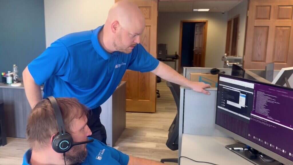 Buffalo IT Services technician assisting a helpdesk engineer at a support workstation